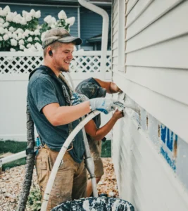 Injection Foam Expert from Mammoth Home Renovations installing RetroFoam insulation in an exterior wall of a white house.